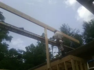 Carpenter setting a ridge beam over a new addition frame — Ice Dam Removal by Roofing Brothers in Gastonia