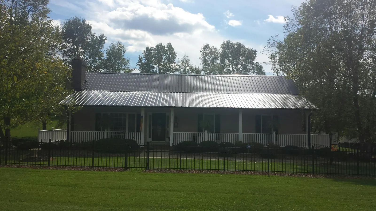 Gray metal roof on a brick ranch with a full width front porch — Gutter Guard Installation work by our crew in Gastonia