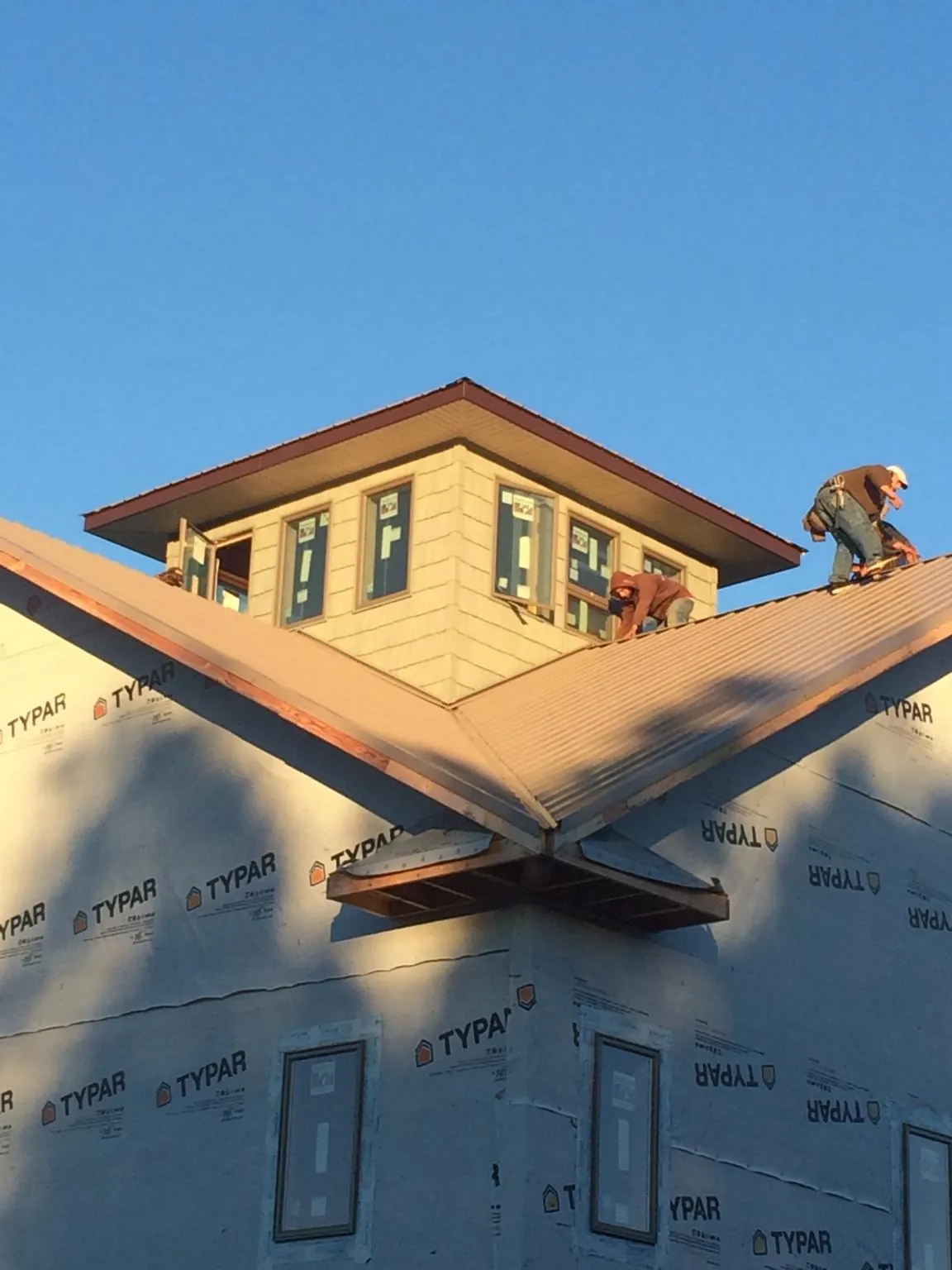 Roofers working around a rooftop cupola on a new metal roof at sunset — Roof Waterproofing in Gastonia by Roofing Brothers